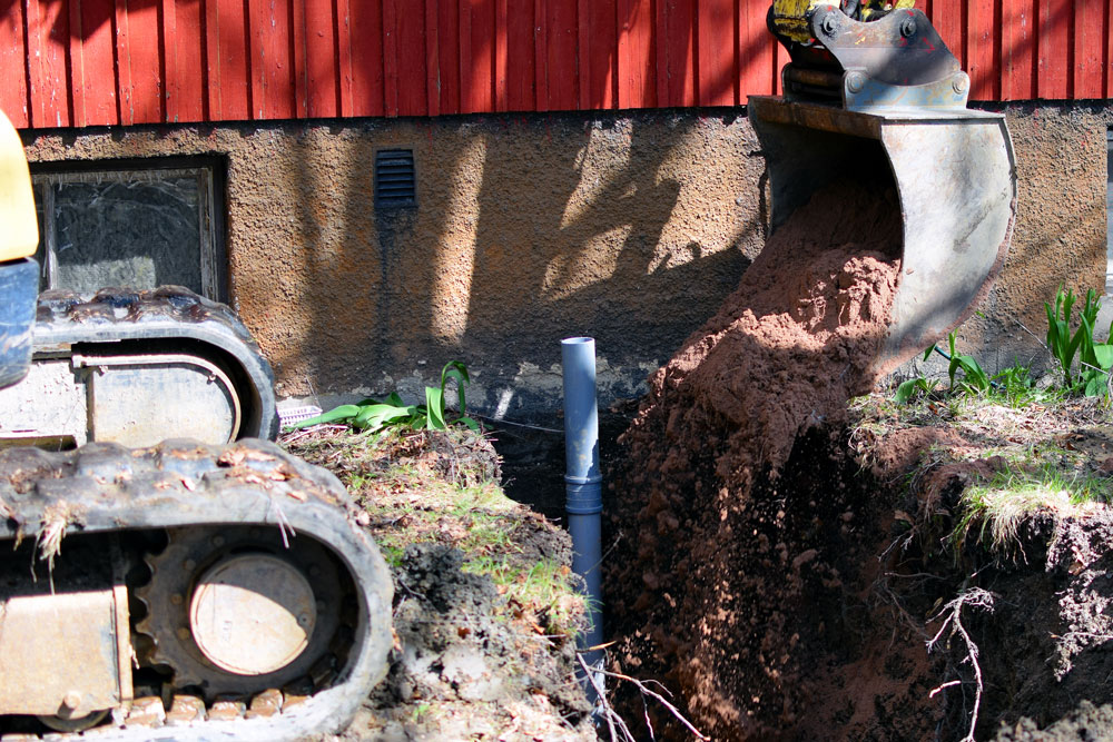 En grävskopa gräver nära ett hus